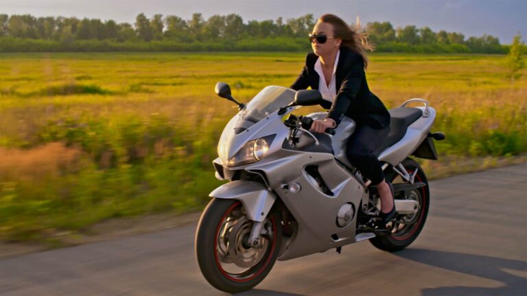 Woman riding motorcycle in on a scenic country road.