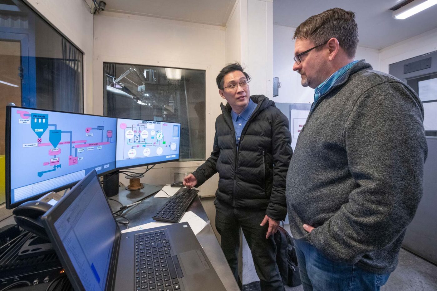 Workers in a control room with computer monitors.